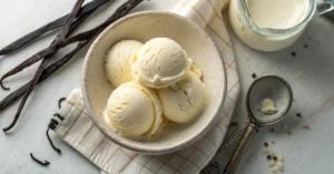 Creamy homemade vanilla ice cream scoops in a rustic ceramic bowl, overhead view, smooth texture visible, surrounded by fresh